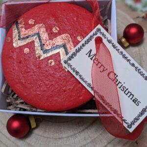 Hand holding a box containing a Christmas bauble macaron